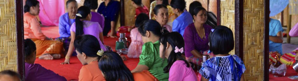 Gruppe von Menschen in traditionellen Gewändern bei einer Zusammenkunft in einem Innenraum, Inle See (UNESCO BIOSPHÄRENRESERVAT) Inle See, Shan Staat Myanmar