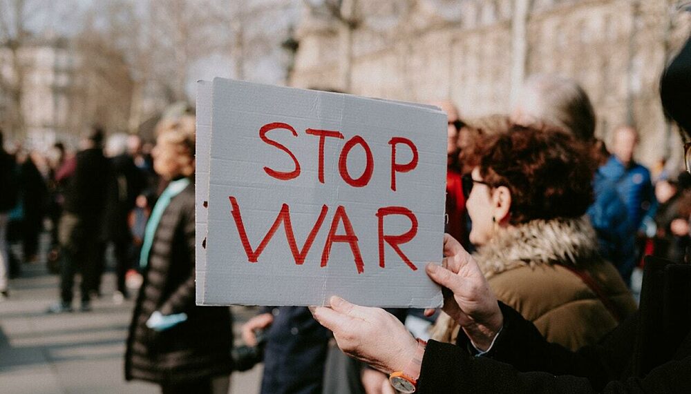 Protestierende halten "stop war" Banner bei einer Demonstration.