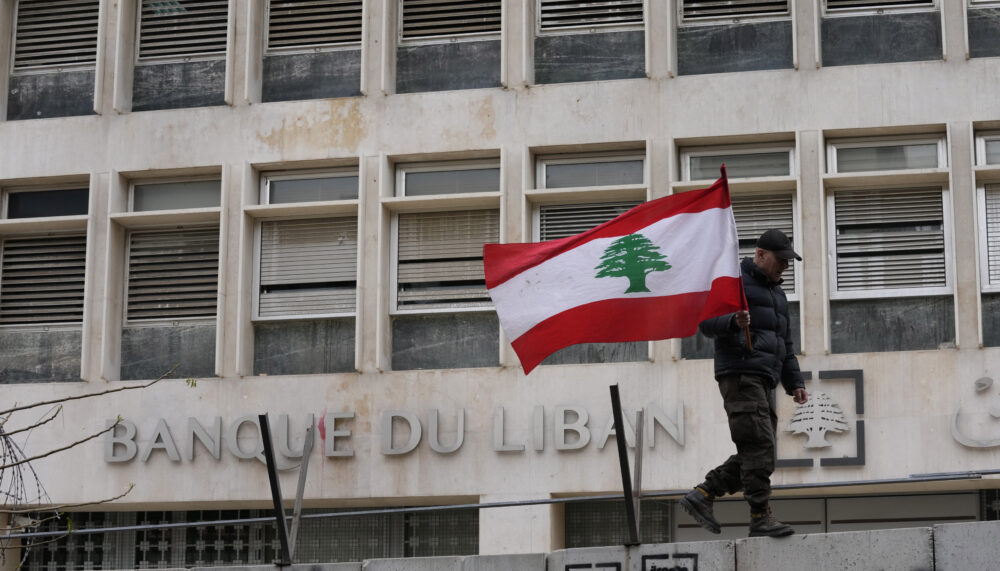 A retired soldier holds a Lebanese flag outside the central bank during a protest demanding better pay and living conditions, in Beirut, Lebanon in March 2023.