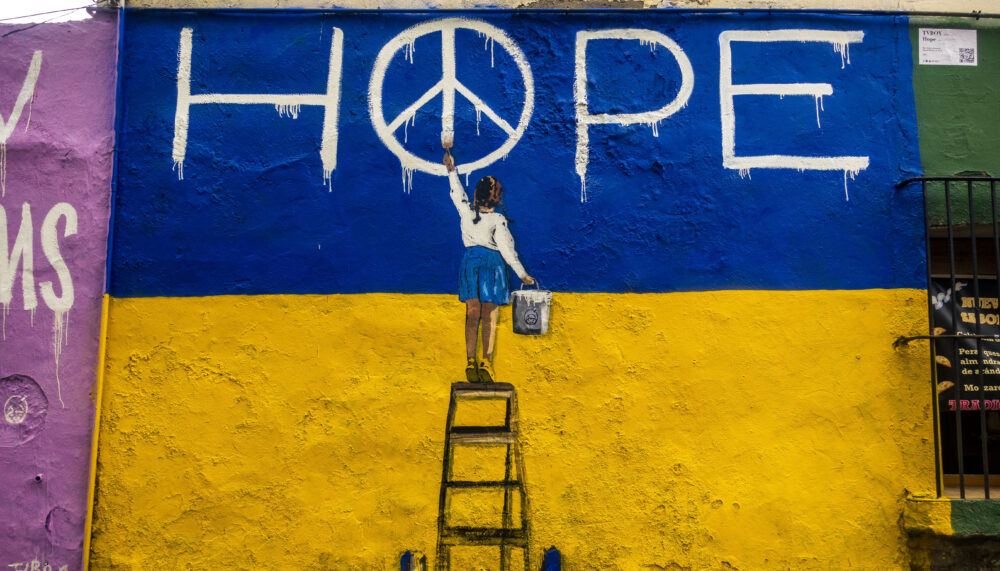 A mural graffiti depicting a little girl in front of the Ukrainian colours writing the word 'HOPE'