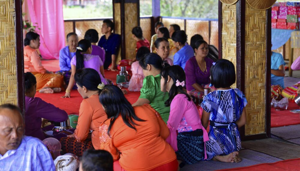 Gruppe von Menschen in traditionellen Gewändern bei einer Zusammenkunft in einem Innenraum, Inle See (UNESCO BIOSPHÄRENRESERVAT) Inle See, Shan Staat Myanmar
