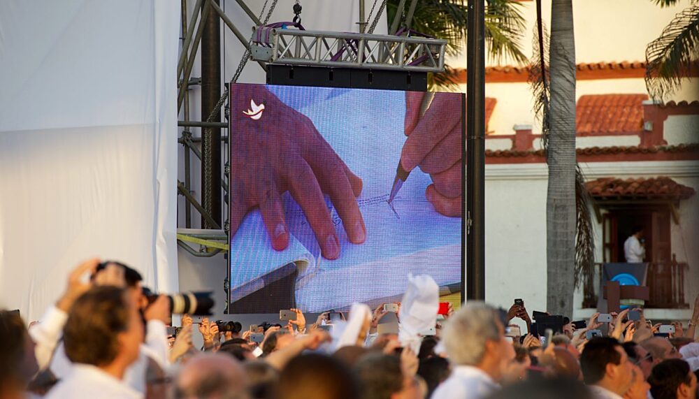 Colombian President Juan Manuel Santos signs a peace accord with FARC leader TimoleónJiménez.
