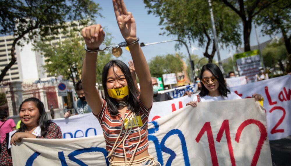 Women raising three fingers into the air at anti-government protests in Bangkok, Thailand.