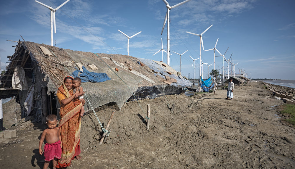 A family in their house in Bangladesh next to a wind farm.